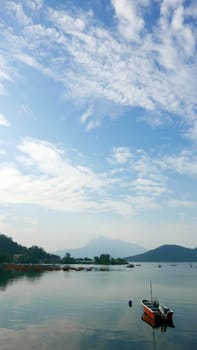 Red fishing boat on peaceful lake in day time