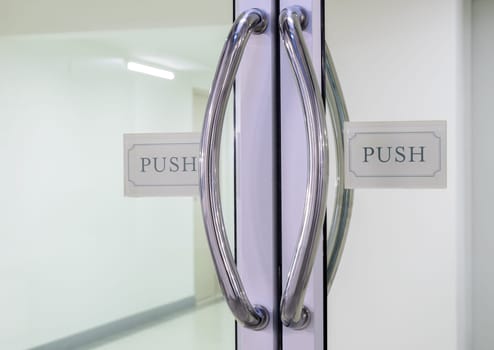 Glass door with chrome handles and push sign on door