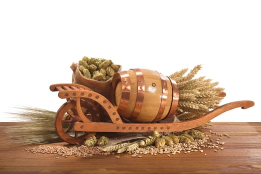 Old barrel with wheelbarrow,wheat,barley,hops and malt against a white background