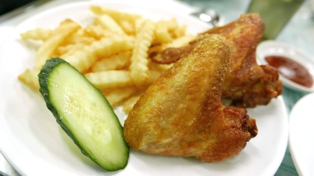 Two chicken wings and fries on the white dish