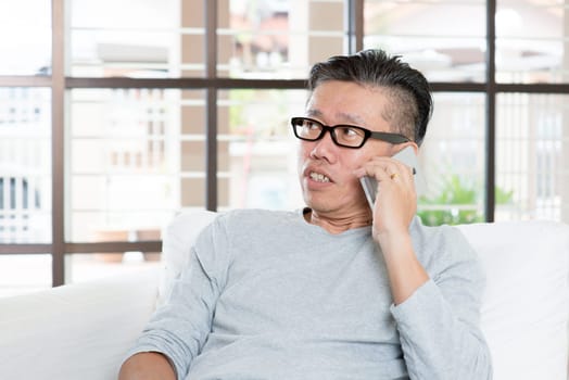 Modern technology, age and people concept. Mature Asian man using smart phone. Living lifestyle at home.
