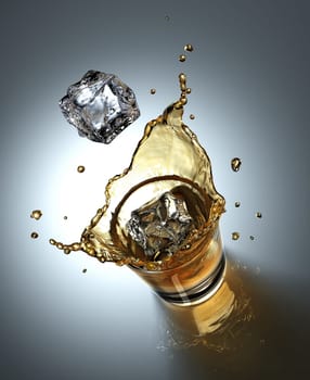 ice cube splashing in a glass full of liquid