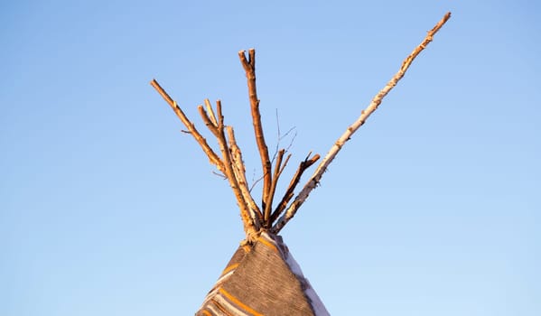 Top of a Tipi with a clear blue sky behind it.