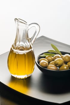 Olive oil and olives on a black plate.