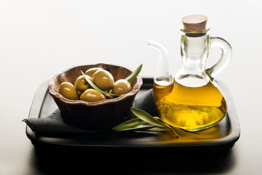 Bottle of premium virgin olive oil and some olives with leaves.
