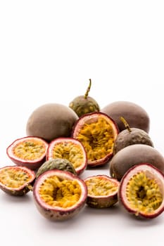 Seven halved and six entire passionfruits grouped on white background. Juicy, yellow and sour passion fruit pulp hanging in its purple rind. Also called purple granadilla. Close up studio shot.