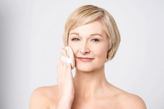 Woman posing to camera while cleansing her face