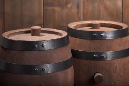 two old wooden barrels with wooden plugs on a dark wood background