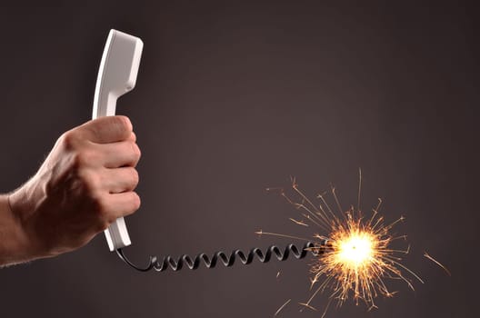 Male hand with a telephone and a burning cable like a fuse