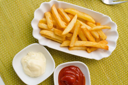 French fries on a white plate with tomato sauce and mayonnaise