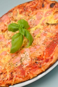 Close up of a pizza with salmon and shrimps, selective focus on foreground