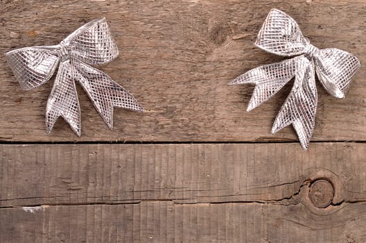 Two silver bows on a rustic wooden background with space for text or image