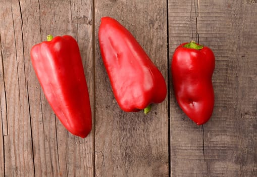 Three red fresh paprika on an old used barn wood