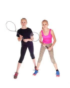 Two young sisters standing isolated for white background with there.tennis racquet in there hands.