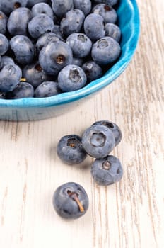 Fresh blueberries in a rustic blue bowl on a wooden table