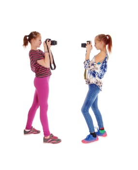 Two young sisters in blue and pink tights standing in profile and taking.pictures of each other, isolated for white background..
