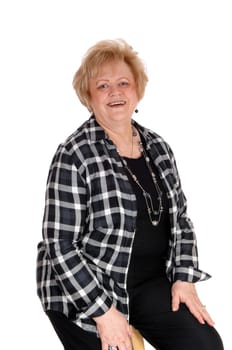 A lovely senior blond woman in a black checkered jacket and black pants .sitting, isolated for white background..
