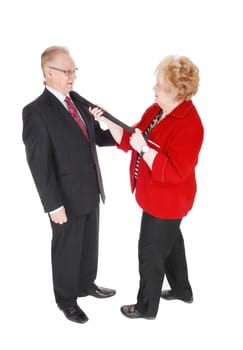 A senior couple he in a suit and she in a red jacked holding the handle of.a umbrella around the mans neck, isolated for white background..
