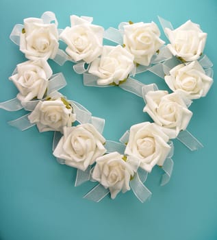 Heart shape of white foam roses on a turquoise leather background