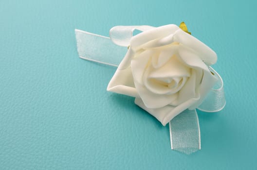 White plasic foam rose on a turquoise leather background with space for text