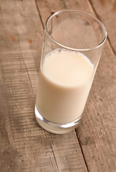 Glass of fresh organic milk on a rustic wooden table