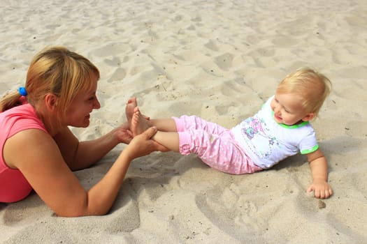 mother plays with her baby plays on the river sand
