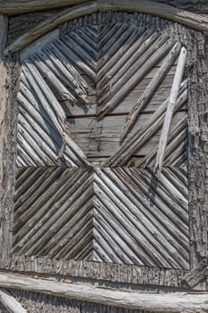 Broken side wall of a building decorated with round wood