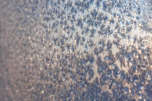 Snowflakes and frost on frozen christmas winter window. Natural color. Selective focus with blur edges of image