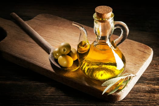 Bottle of premium virgin olive oil and some olives with leaves.