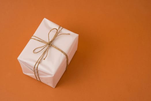 Simple natural white vintage gift box top view on orange background with copy space.