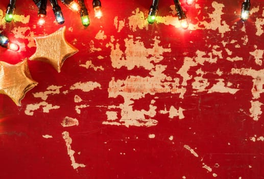 Holiday concept backdrop template, gold paper star decoration and Christmas lights on empty retro grunge wood background.
