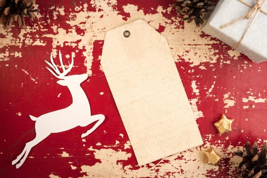 Merry Christmas vintage top view fabric hang tag label template with paper cut deer silhouette and holiday decoration elements on grunge wood background. Includes clipping path.