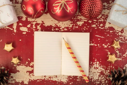 Christmas card background, top view notebook template with pencil and vintage holiday decoration ornaments on hipster grunge wood texture.