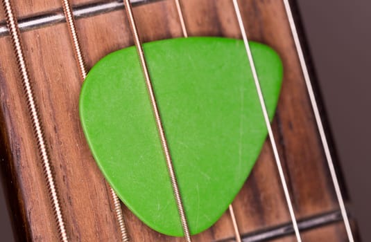 Green Plectrum Stuck in Steel Strings close up macro image.