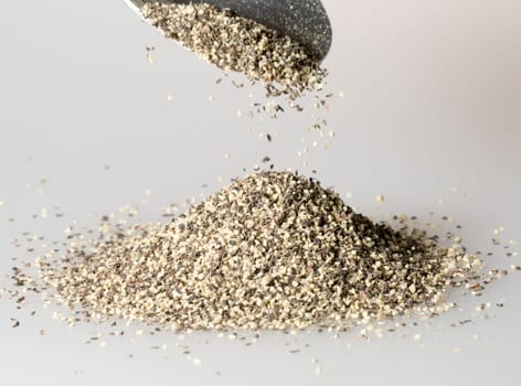 Black Pepper Falling from tablespoon close up.