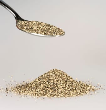 Ground Pepper on Tablespoon with a pile of black pepper beneath.