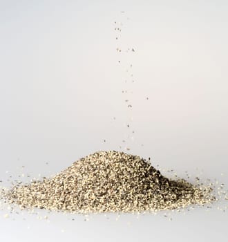 Black Pepper Grains Falling into Pile close up.