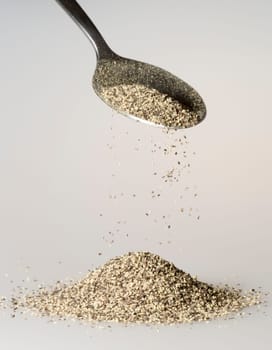 Black Pepper Falling from tablespoon close up.