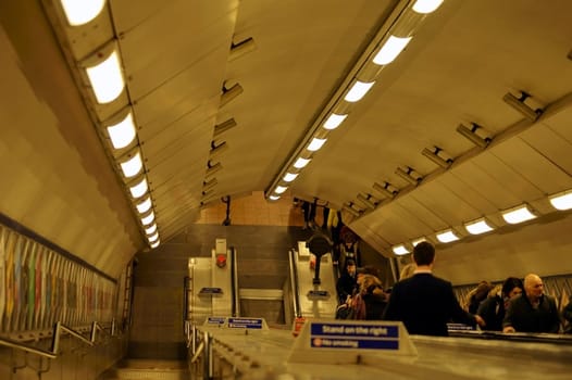 London,United Kingdom - March 31,2015: Passers-by leave the underground via an escalator tunnel on March 31,2015 in London.