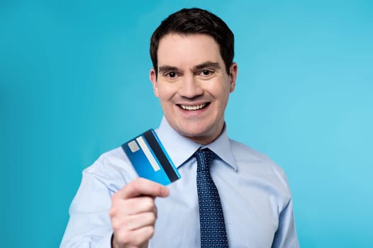 Middle aged man lending his plastic card to camera