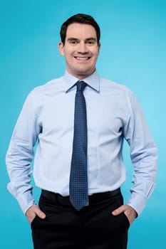 Confident businessman posing to camera against blue