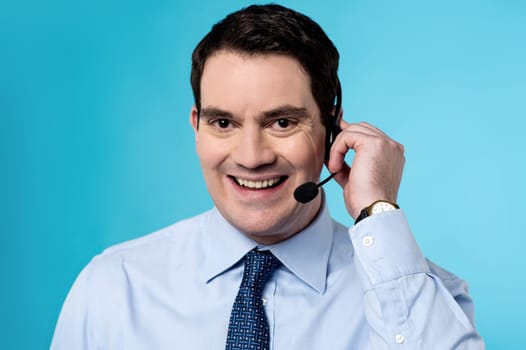 Happy male executive posing to camera with headset