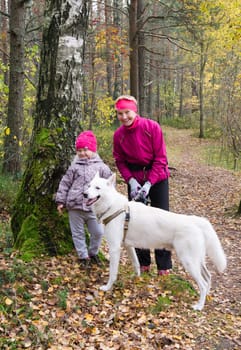 Granny with her granddaughter and a dog walk in autumn Park