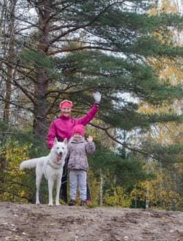 Granny with her granddaughter and a dog walk in autumn Park
