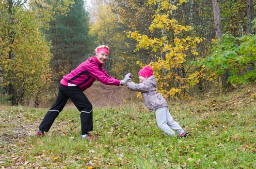 Woman with girl doing aerobics in the autumn park