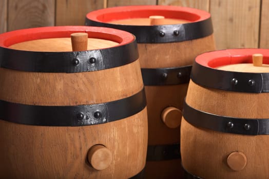 three old beer barrels with wooden plugs on a wooden background