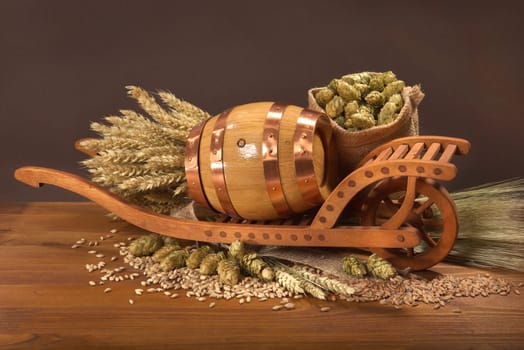 Old barrel with wheelbarrow,wheat,barley,hops and malt