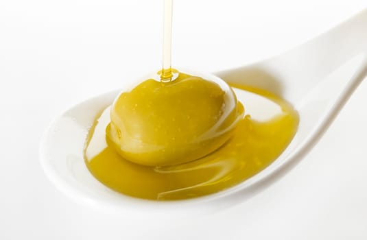 Virgin olive oil pouring on white spoon.