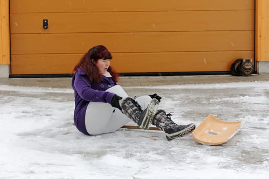 Risk of accidents when clearing snow. A woman has slipped while shoveling snow
