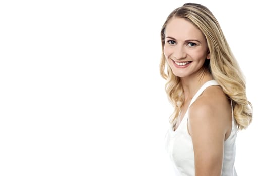 Smiling pretty girl posing sideways  to camera against white background
